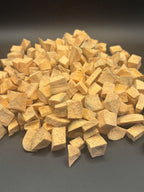 Pile of irregularly cut dried yellow root vegetable pieces on dark surface