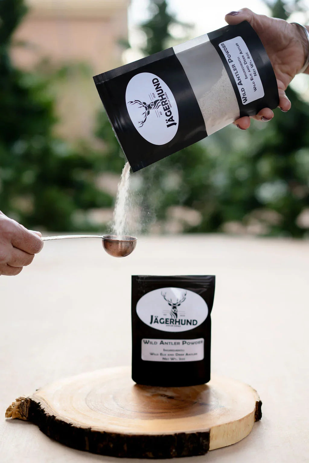 Pouring Jägerhund Wild Antler Powder from black pouch into measuring spoon outdoors
