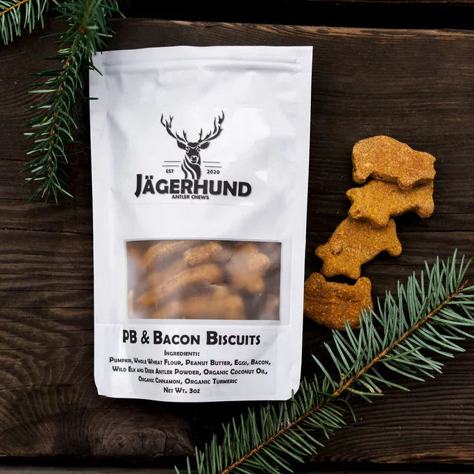 Jägerhund PB & Bacon Biscuits dog treats packaging with deer-shaped biscuits on wooden surface with pine branches