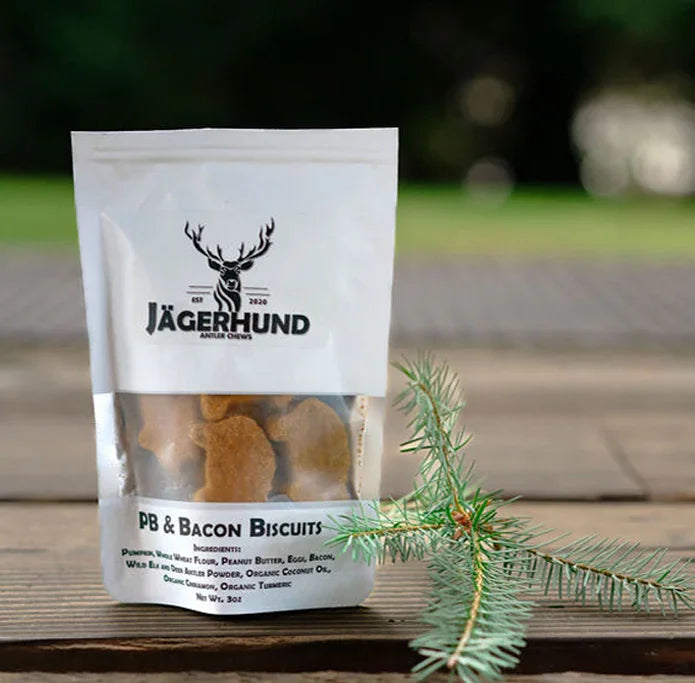 Jägerhund PB & Bacon Biscuits dog treats package on wooden surface with pine branch