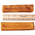 Two dog churpi cheese chews with a Fiskars ruler showing their dimensions on a white background.