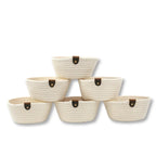 Set of six white cotton rope storage baskets with brown leather handles stacked in pyramid